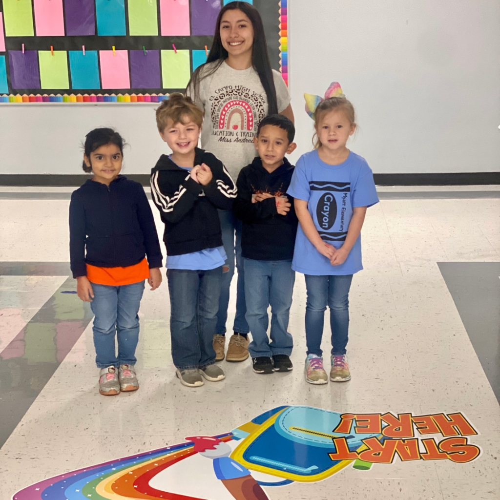 Andrea posing with 5 younger students by the sensory path