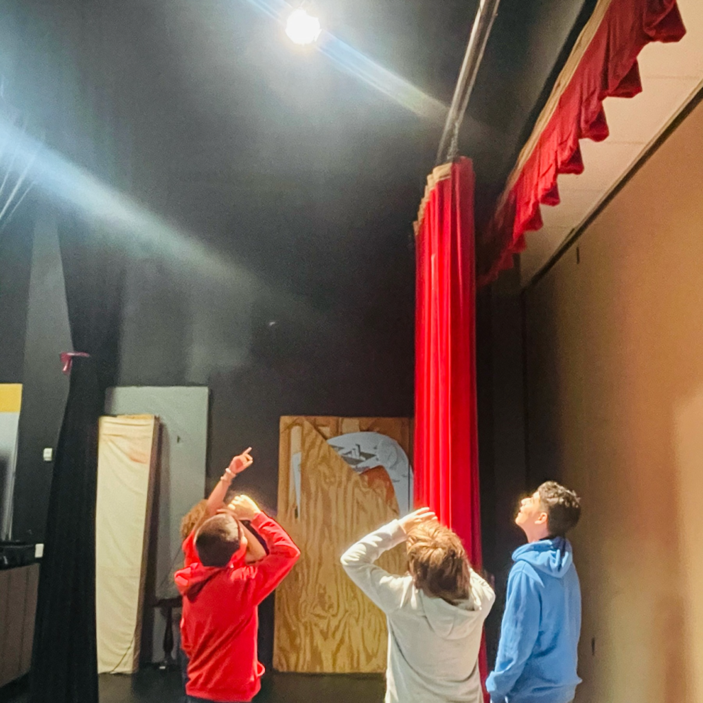 3 students looking at stage lights